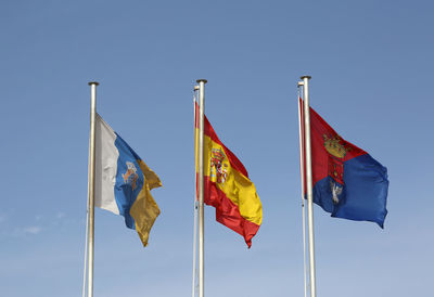 Low angle view of flags against clear blue sky