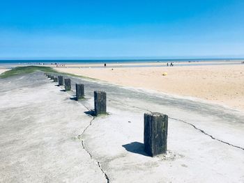 Wooden posts on beach against sky