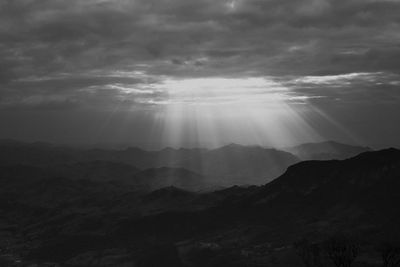 Sunlight streaming through clouds over landscape