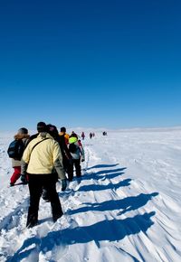 People on snowy mountain against clear blue sky