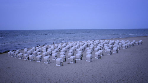 Hooded chairs at beach against clear sky at dusk