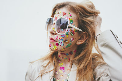 Woman with stickers on face standing eyes closed in front of white background