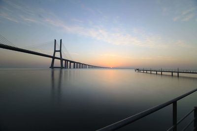 Bridge over sea against sky during sunset