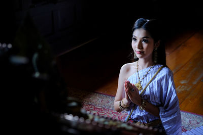 Beautiful young woman with hands clasped praying in temple