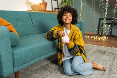 Portrait of young woman sitting on sofa at home