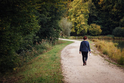 Rear view of woman walking on dirt road