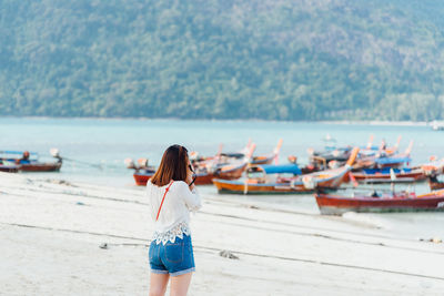 Woman standing at beach against sky