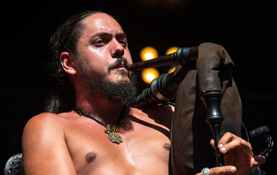 Close-up of shirtless man playing bagpipe during concert
