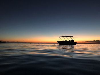 Silhouette boat in sea against clear sky during sunset