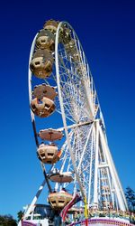 Low angle view of ferris wheel against clear blue sky