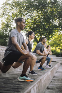 Focused male and female friends practicing lunges on steps