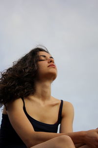 Portrait of young woman looking away against sky