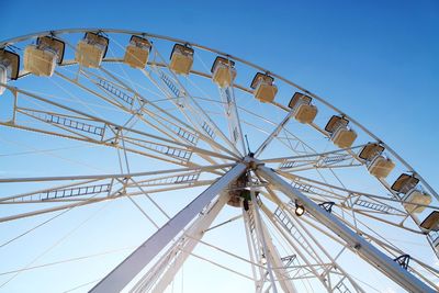 Low angle view of ferris wheel against clear blue sky