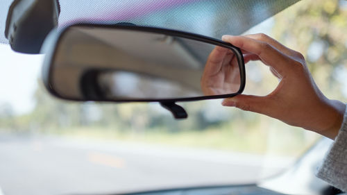 Close-up of hand adjusting rear-view mirror in car