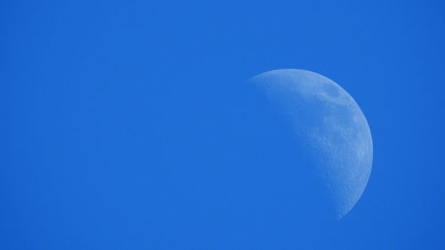 Low angle view of the moon against clear blue sky