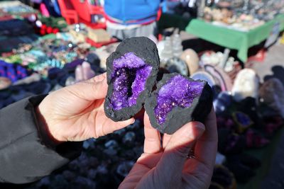 Cropped hand of man holding amethyst outdoors