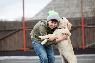 Boy playing with dog outdoors