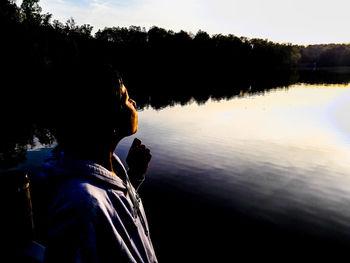 Portrait of silhouette man by lake against sky during sunset