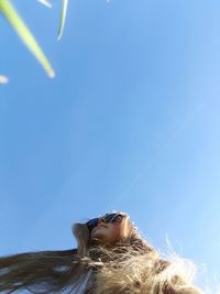 Close-up of young woman against blue sky