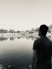 Rear view of man looking at lake against sky