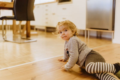 Portrait of girl sitting on hardwood floor at home