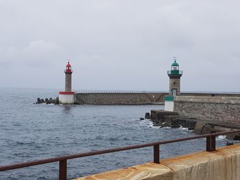 Lighthouse by sea against sky