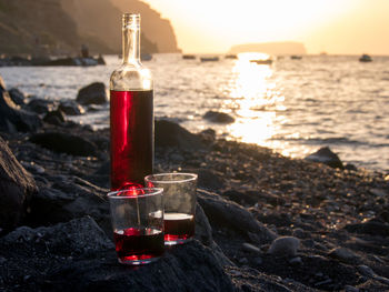 Glass of water bottle on beach during sunset