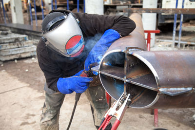 Rear view of man working on metal