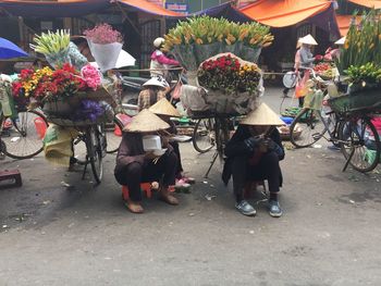 People sitting on street by flowers