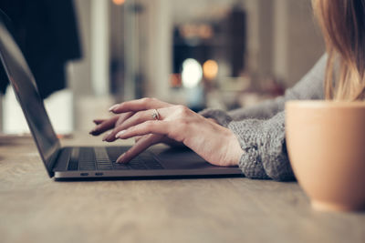 Close-up of woman using laptop on table