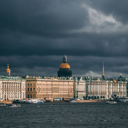 View of city by sea against storm clouds