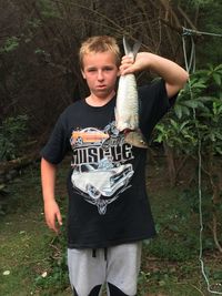 Portrait of teenage boy holding fish while standing on field