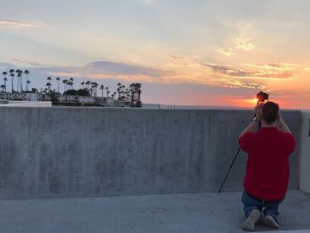 Rear view of woman photographing at sunset