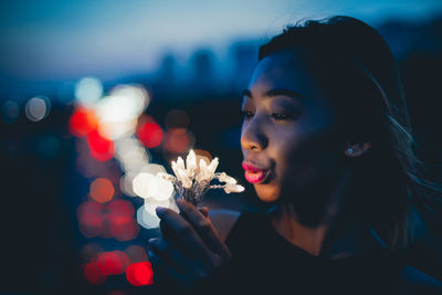 Woman holding illuminated lights at night