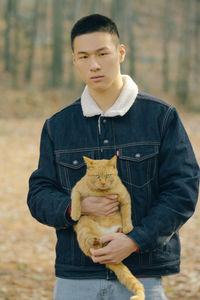 Portrait of young man with cat standing on land