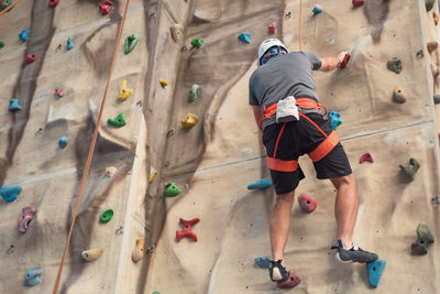 Full length rear view of man climbing rope