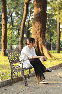 Side view of woman sitting on bench in park