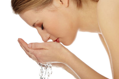 Close-up of woman drinking water against white background