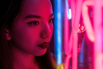 Close-up of young woman by illuminated lights