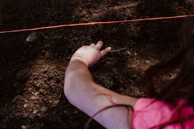 Close-up of girl hand digging mud on land
