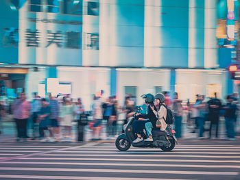 Side view of man riding motor scooter on street