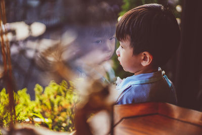 Portrait of kid stand still near window glass and looking to outside. little child reflecting.