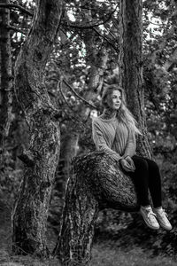 Portrait of man sitting on tree trunk in forest