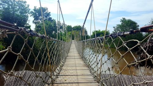 Footbridge over trees against sky