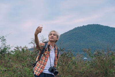 Young man taking selfie while standing against mountain