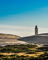 Lighthouse on beach against sky