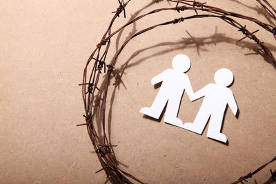 High angle view of barbed wire with paper chain on brown table