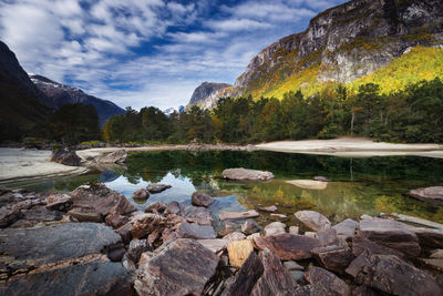 Rocks by lake against sky