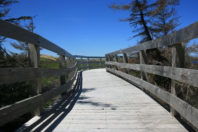 Footbridge amidst trees against clear sky