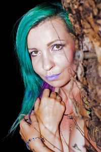 Portrait of naked woman with green dyed hair standing by tree at night